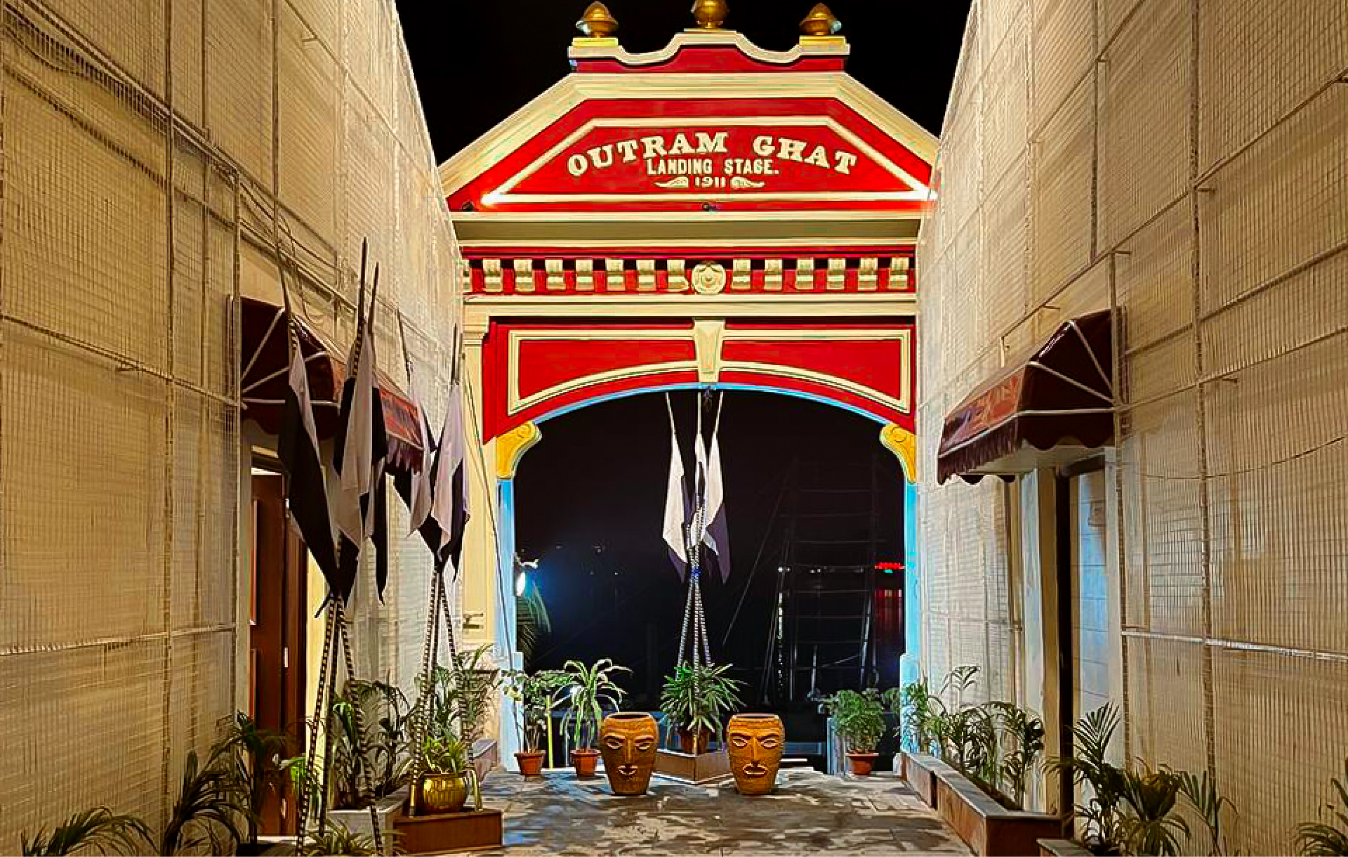 Restored Outram Ghat landing stage with illuminated red and gold heritage arch on the Hooghly riverfront, Kolkata